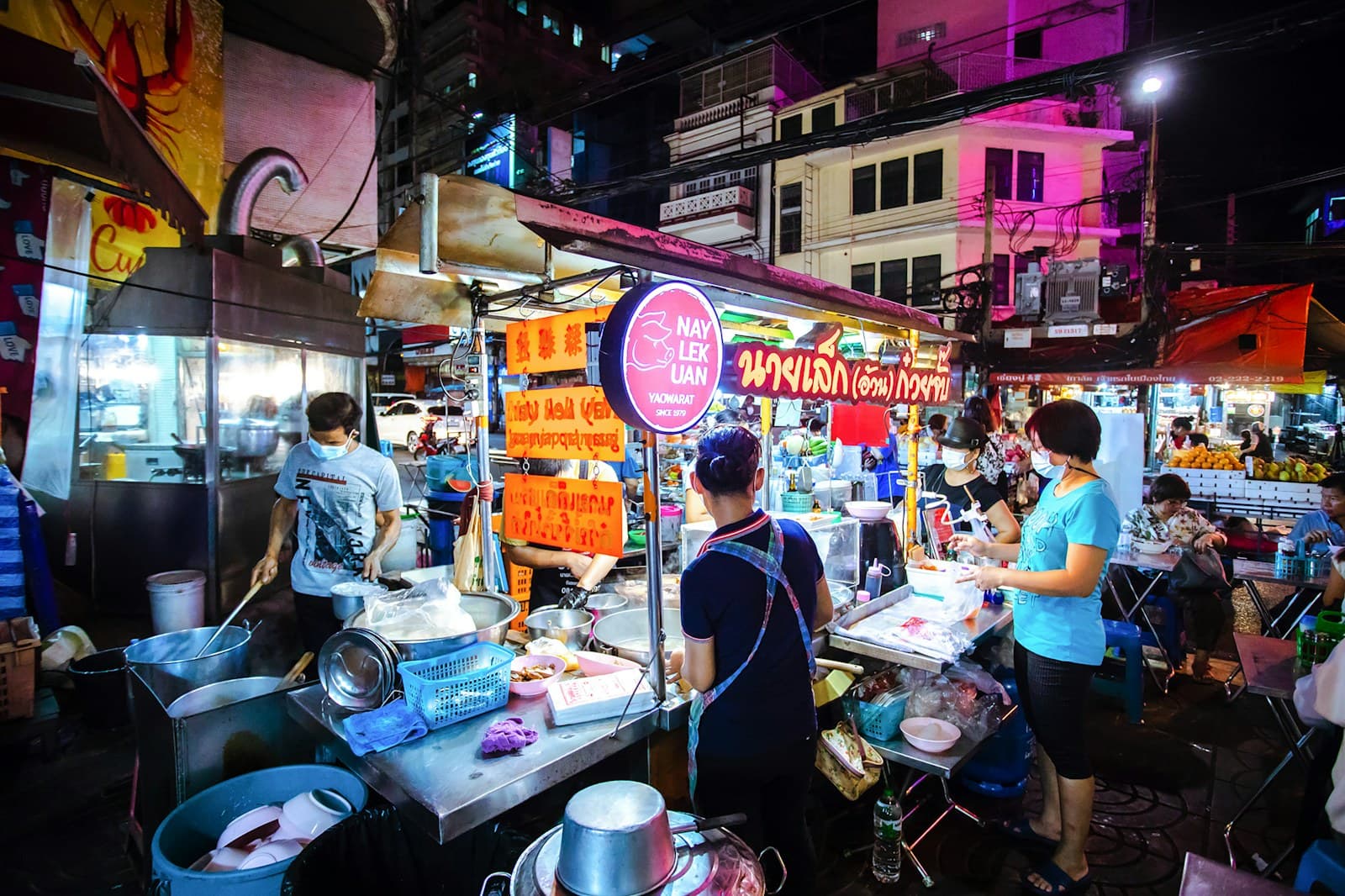 Stand de street food à Bangkok la nuit, sous les néons