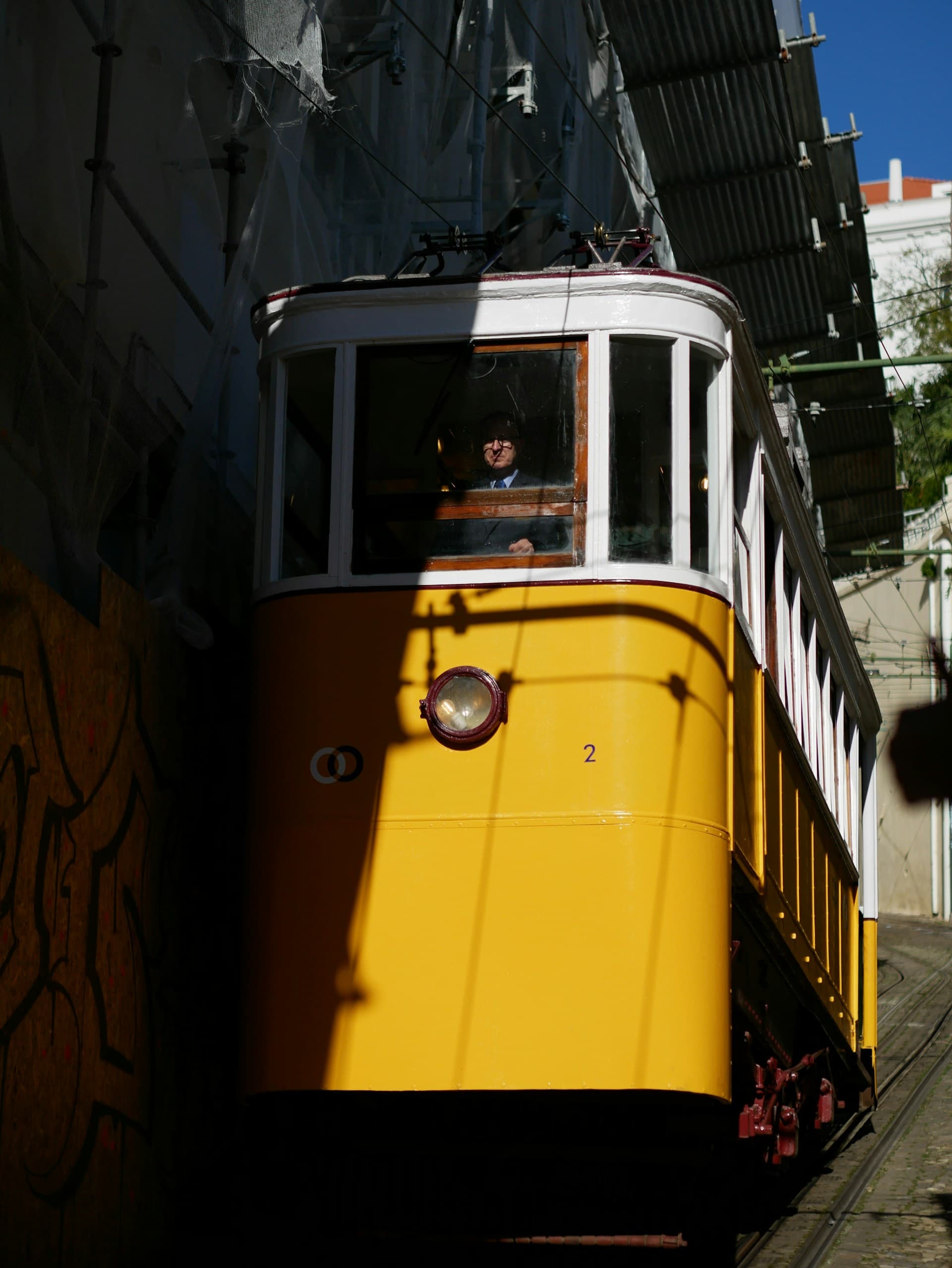 Iconic yellow tram on a hilly Lisbon street